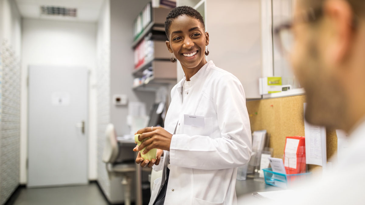 Lady in lab coat smiling to a work colleague